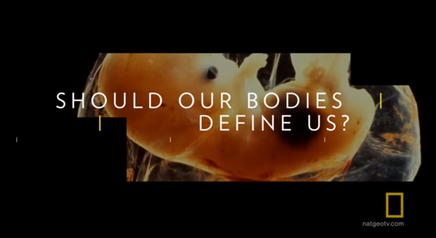 Screenshot from the trailer, a fetus with the words superimposed, Should our bodies define us?