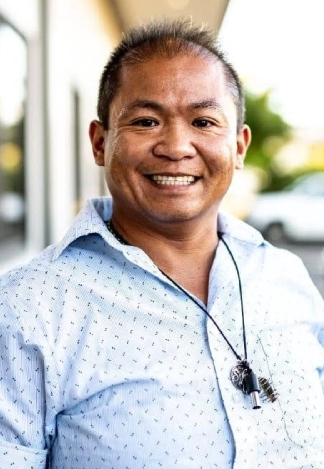 Photo of Chi Mei Tam in a light collared shirt, looking toward the camera and smiling